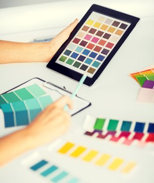 Color swatches laid out on a desk beside a tablet